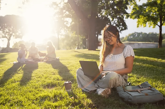 Woman sat on her laptop in a park