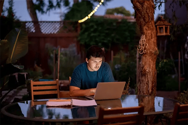 a young man studying in his garden late at night 