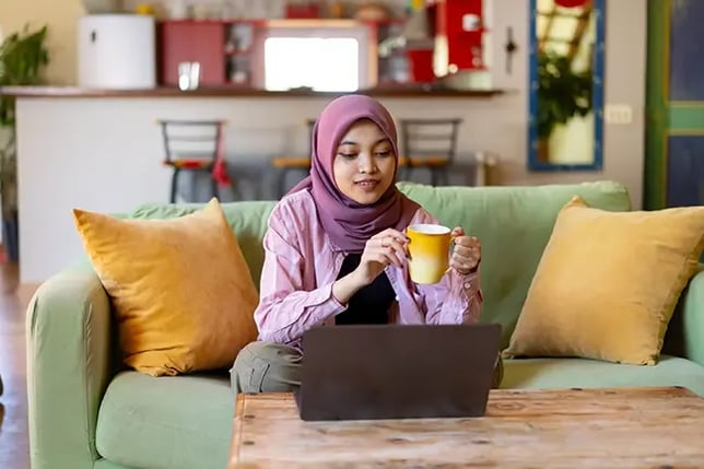 woman working on her couch with a cup of tea