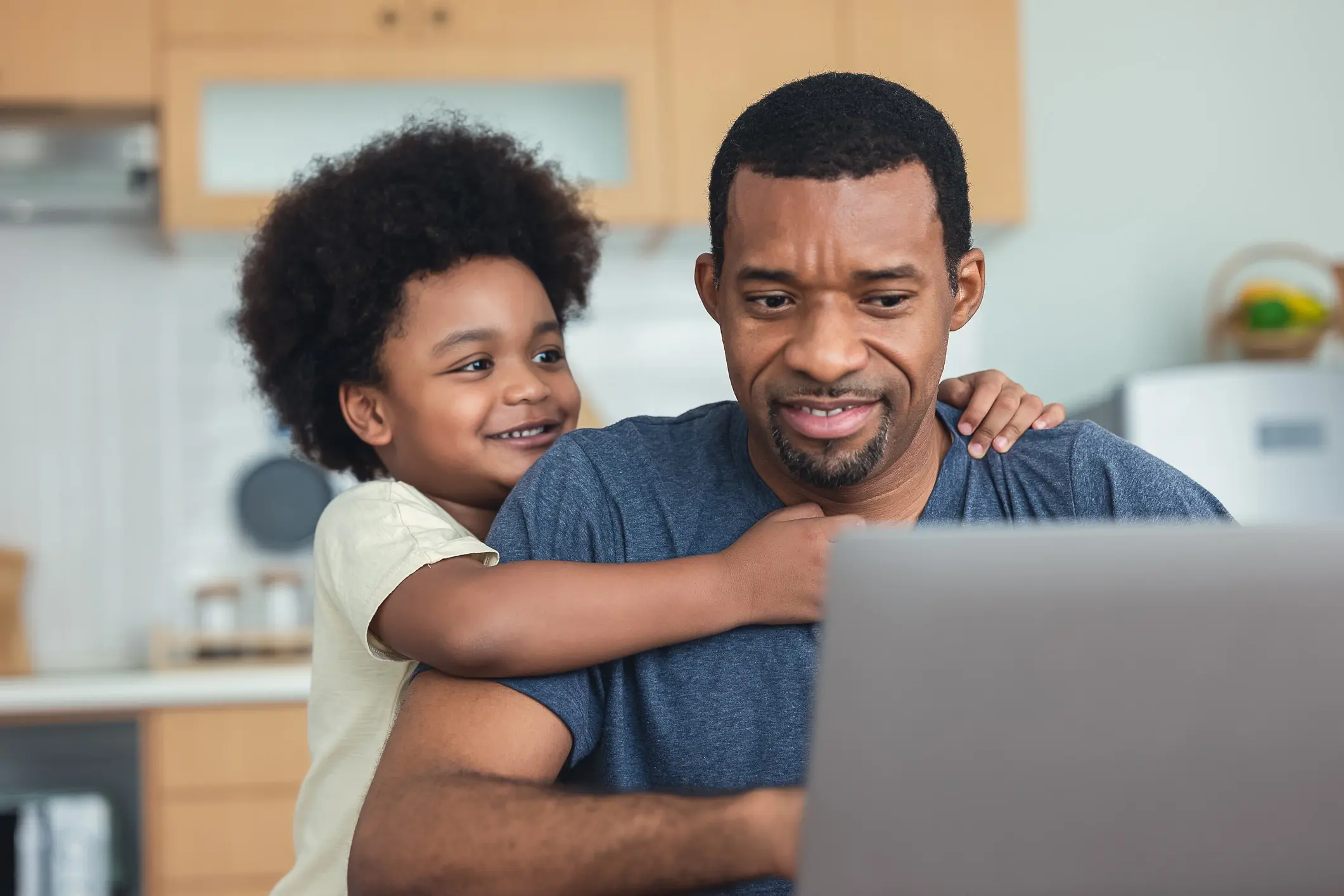 father doing his work on the laptop with his infant son next to him