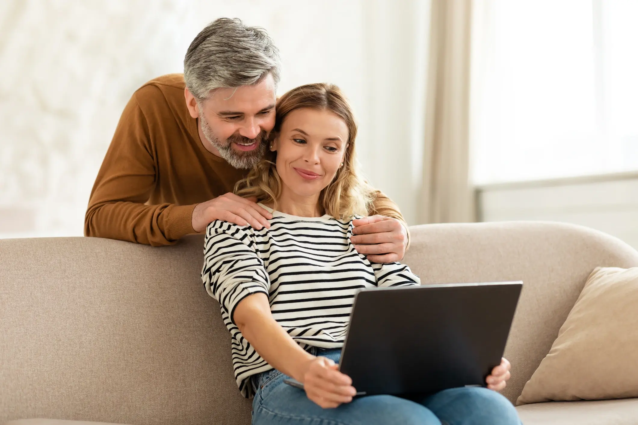 happy looking couple the woman is doing work on her laptop