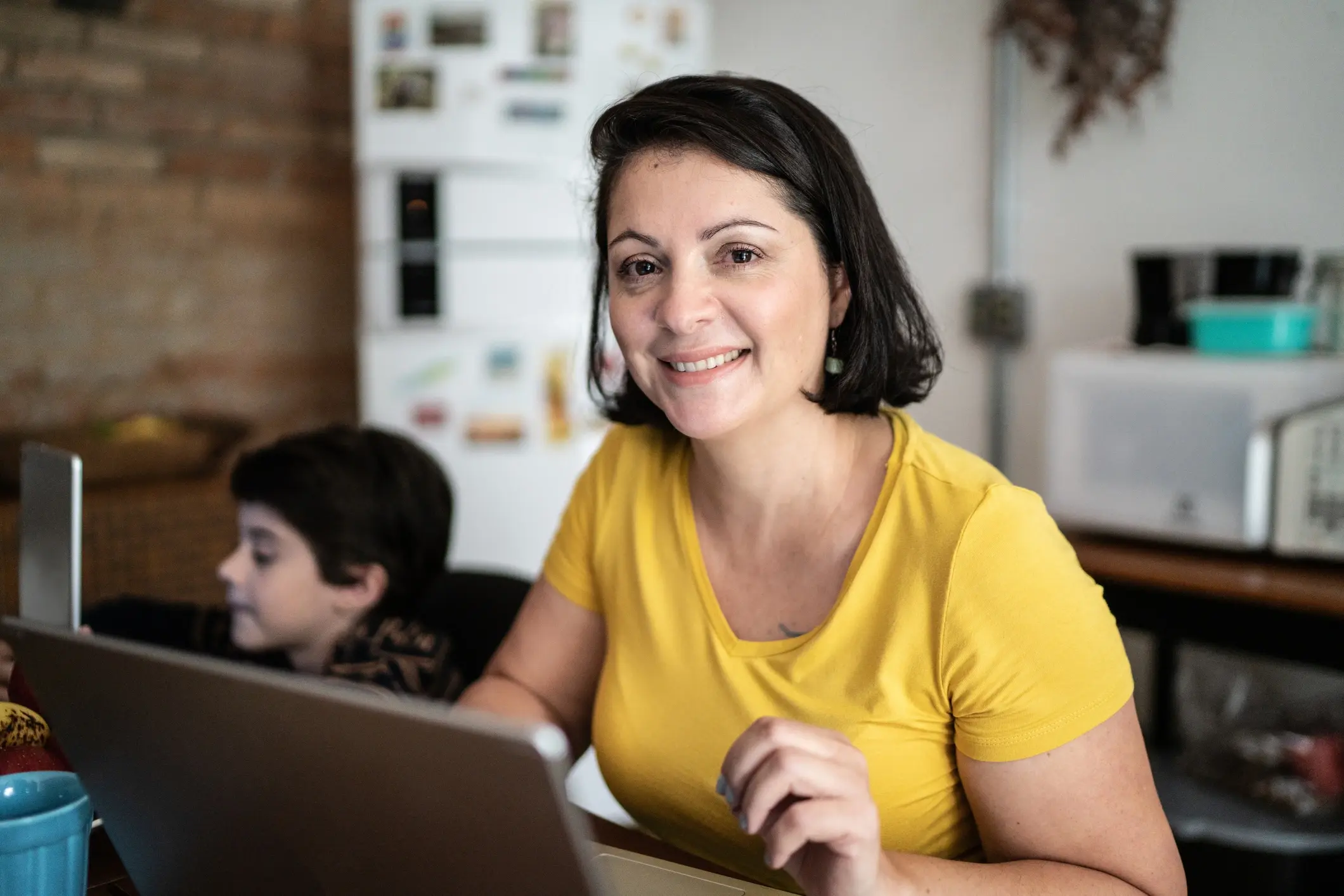 happy mother working on her assignment while her son is in the background