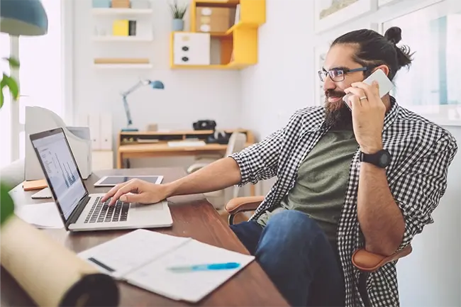 man on a call whilst using his laptop