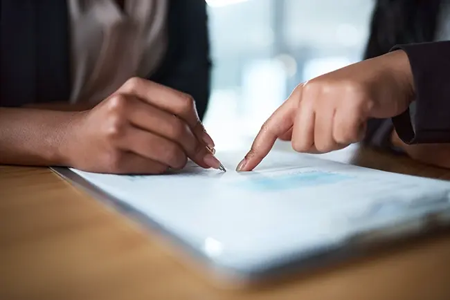 two people pointing at a piece of work